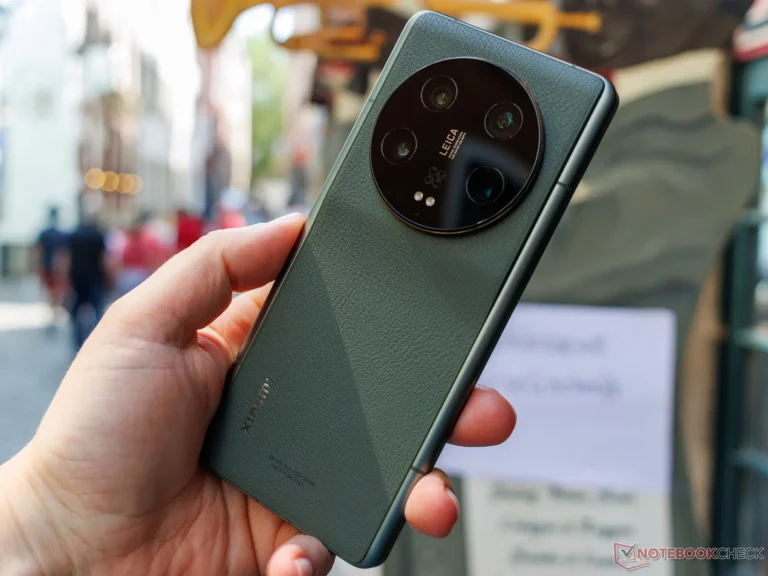 Hand holding a Xiaomi 13 Ultra smartphone showing the green vegan leather back and circular Leica camera module outdoors